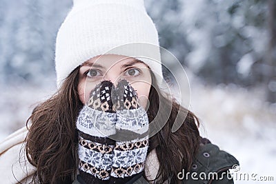 Young girl, woman in knitted mittens feels cold. Walking in beautiful winter forest among trees, firs, covered with snow. Stock Photo