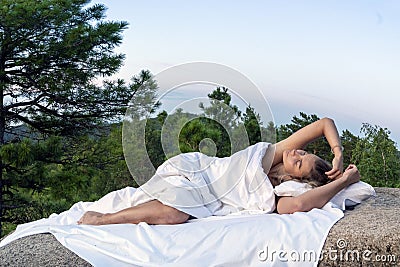 A young girl woman sleeps on a white sheet in the forest on the rocks of the bark in bed, close-up. Sleep and comfort Stock Photo