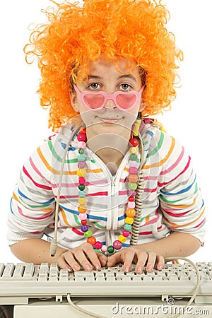 Young girl working on a computer and disguised with fun glasses and orange hair Stock Photo