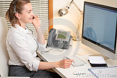 A young girl works in a call center. For a workplace with a telephone. A microphone with a microphone. Support service. Help desk Stock Photo