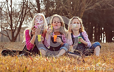 Young girls kids sisters blowing bubbles with soap in a farm fie Stock Photo