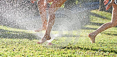 Young girls playing jumping in a garden water lawn sprinkler Stock Photo