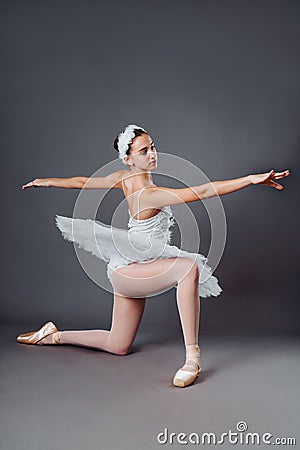 A young graceful ballerina dressed in professional attire, pointe shoes and a white tutu, demonstrates dance skills. Beautiful Stock Photo