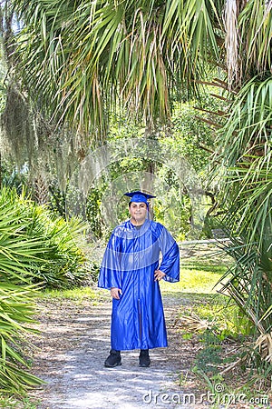 Young Graduate Posing With Cap And Gown In A Tropical Setting Stock Photo