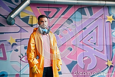 Young graffiti painter standing near the wall with his paintings with copy space Stock Photo