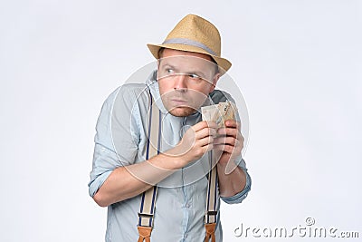 Young greedy man hiding money for rainy day. Stock Photo