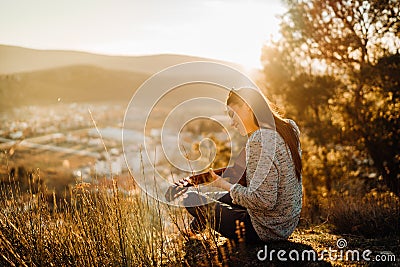 Young guitarist playing acoustic guitar and enoying the sunset.Learning to play an instrument.Singer-songwriter in nature Stock Photo