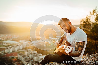 Young guitarist playing acoustic guitar and looking to sunset.Searching inspiration.Music creator.New artist.Musical talent. Stock Photo