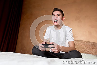 Young guy emotionally plays a computer game with the joystick Stock Photo