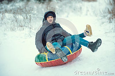 Young guy and a girl ski tubing in the winter ride down a hill Stock Photo