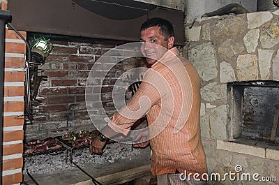 Young guy grills meat in a fireplace on an open fire Stock Photo