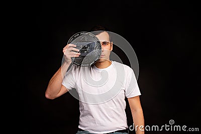 A young guy holds a symbol of the DASH coin, a modern currency for exchange and purchases Editorial Stock Photo