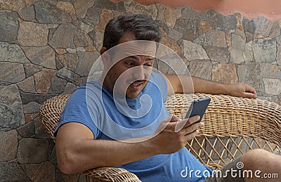 Young guy looking cellphone worried reading the news and having feeling of doubt and confused. Disappointment man holding device Stock Photo