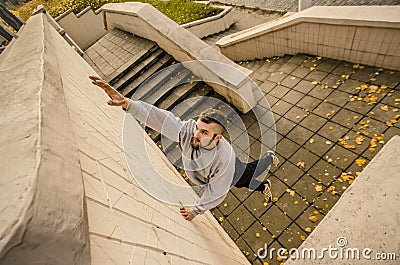 A young guy overcomes obstacles, climbing on concrete walls Stock Photo