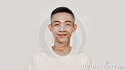 Young guy. Portrait of young asian man with clean shaven face smiling at camera isolated over white background. Beauty Stock Photo