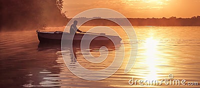 A young guy rides a boat on a lake during a golden sunset. Image of silhouette, Rower at sunset. Man rowing a boat in backlight of Stock Photo