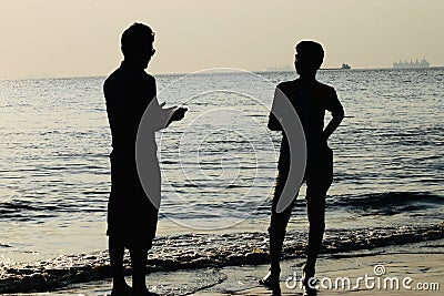 Young guys standing around a sea beach area in the afternoon Editorial Stock Photo