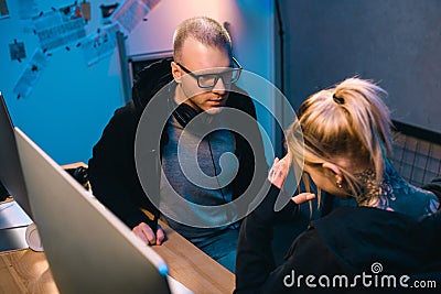 young hacker talking with depressed accomplice at workplace Stock Photo