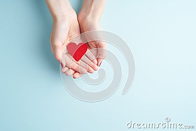 A person holding red heart in hands, donate and family insurance concept, on aquamarine background, copy space top view Stock Photo