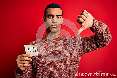 Young handsome african american man holding reminder paper with yes message with angry face, negative sign showing dislike with Stock Photo