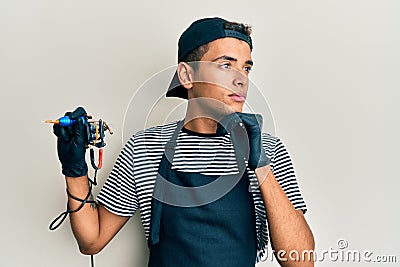 Young handsome african american man tattoo artist wearing professional uniform and gloves holding tattooer machine with hand on Stock Photo