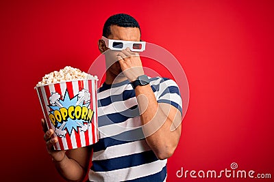 Young handsome african american man watching movie using 3d glasses eating popcorns smelling something stinky and disgusting, Stock Photo