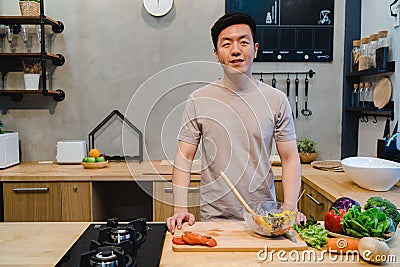 Young handsome asian man prepare salad food and cooking in the kitchen. Stock Photo