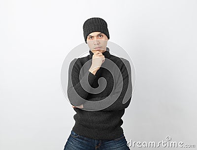 Young handsome asian man wearing grey sweater and beanie thinking an idea while looking to camera on white background. Stock Photo