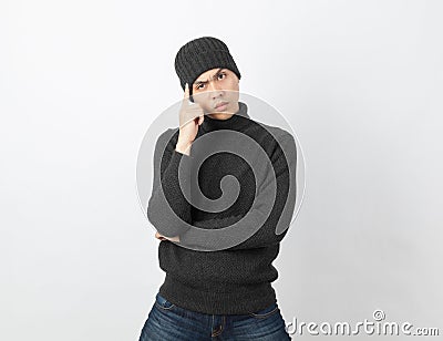 Young handsome asian man wearing grey sweater and beanie thinking an idea while looking to camera Stock Photo