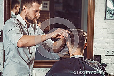 Young handsome barber making haircut of attractive man in barbershop Stock Photo