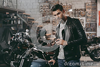 young handsome biker in black leather jacket with classic motorbike Stock Photo