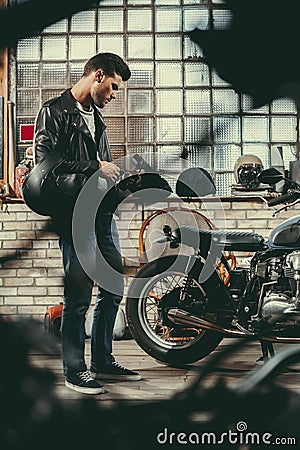 young handsome biker in black leather jacket with classic motorcycle Stock Photo