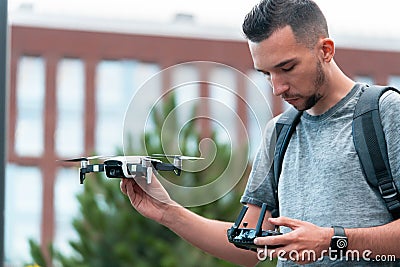 Young Handsome Brunette Man Launching Drone Quadcopter and Looking At Remote Controller Joystick. Urban Stlilysh Stock Photo