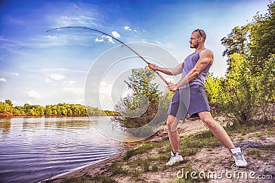 Young handsome brutal caucasian man in casual outfit fishing on Stock Photo