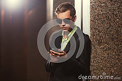 Young handsome business man in black blazer using smart phone Stock Photo