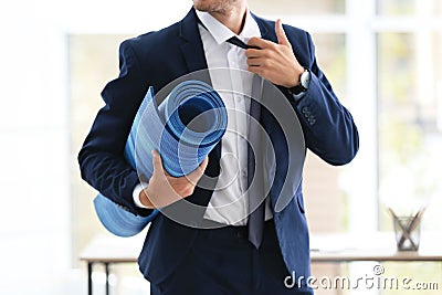 Young handsome businessman holding yoga mat in office Stock Photo