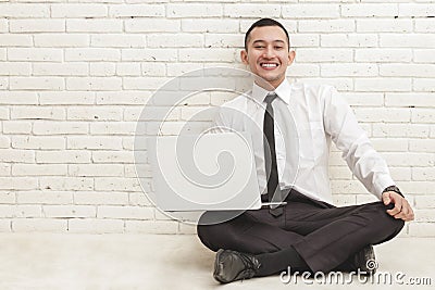 Young handsome businessman with laptop smiling and sitting on th Stock Photo