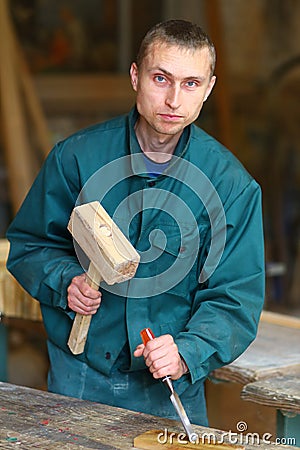 Young handsome carpenter works with a hammer and chisel Stock Photo