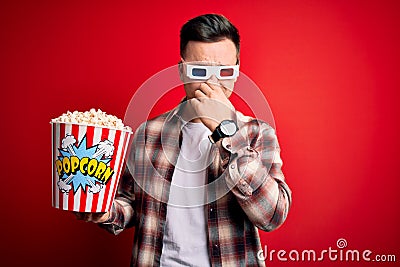 Young handsome caucasian man wearing 3d movie glasses and eating popcorn smelling something stinky and disgusting, intolerable Stock Photo