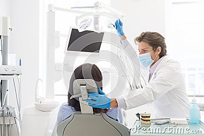 Young handsome dentist comforting female patient sitting in chair Stock Photo