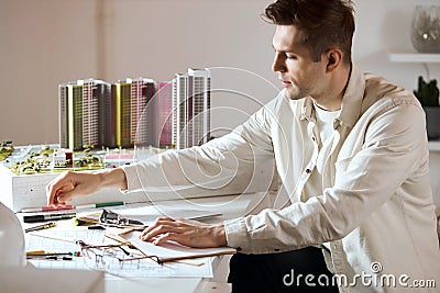 Young handsome fair-haired achitect sitting at the tabel and working on project Stock Photo