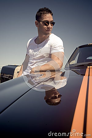 Young handsome guy leaning on muscle car with stripes Stock Photo