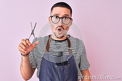 Young handsome hairdresser man wearing apron over pink isolated background scared in shock with a surprise face, afraid and Stock Photo