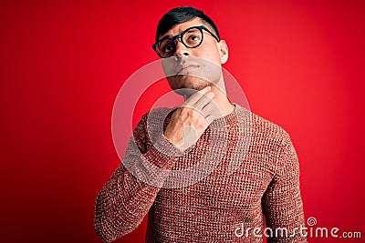 Young handsome hispanic man wearing nerd glasses over red background Touching painful neck, sore throat for flu, clod and Stock Photo