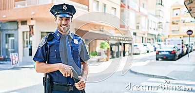 Young handsome hispanic policeman wearing police uniform smiling happy Stock Photo