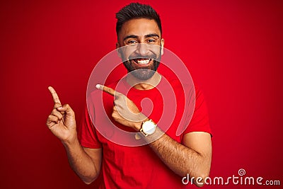 Young handsome indian man wearing t-shirt over isolated red background smiling and looking at the camera pointing with two hands Stock Photo