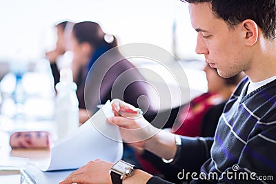 Young, handsome male college student sitting in a classroom full Stock Photo