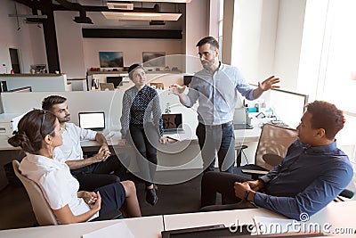 Millennial male leader working with diverse team at office. Stock Photo