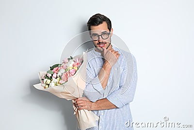 Young handsome man with beautiful flower bouquet on light Stock Photo