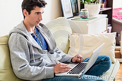 Young handsome man browsing the internet on laptop at home Stock Photo